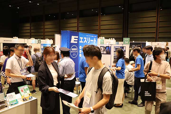 THE GOLD ONLINEの過去開催会場。展示ブースで資料を見ながら説明を聞く来場者の様子